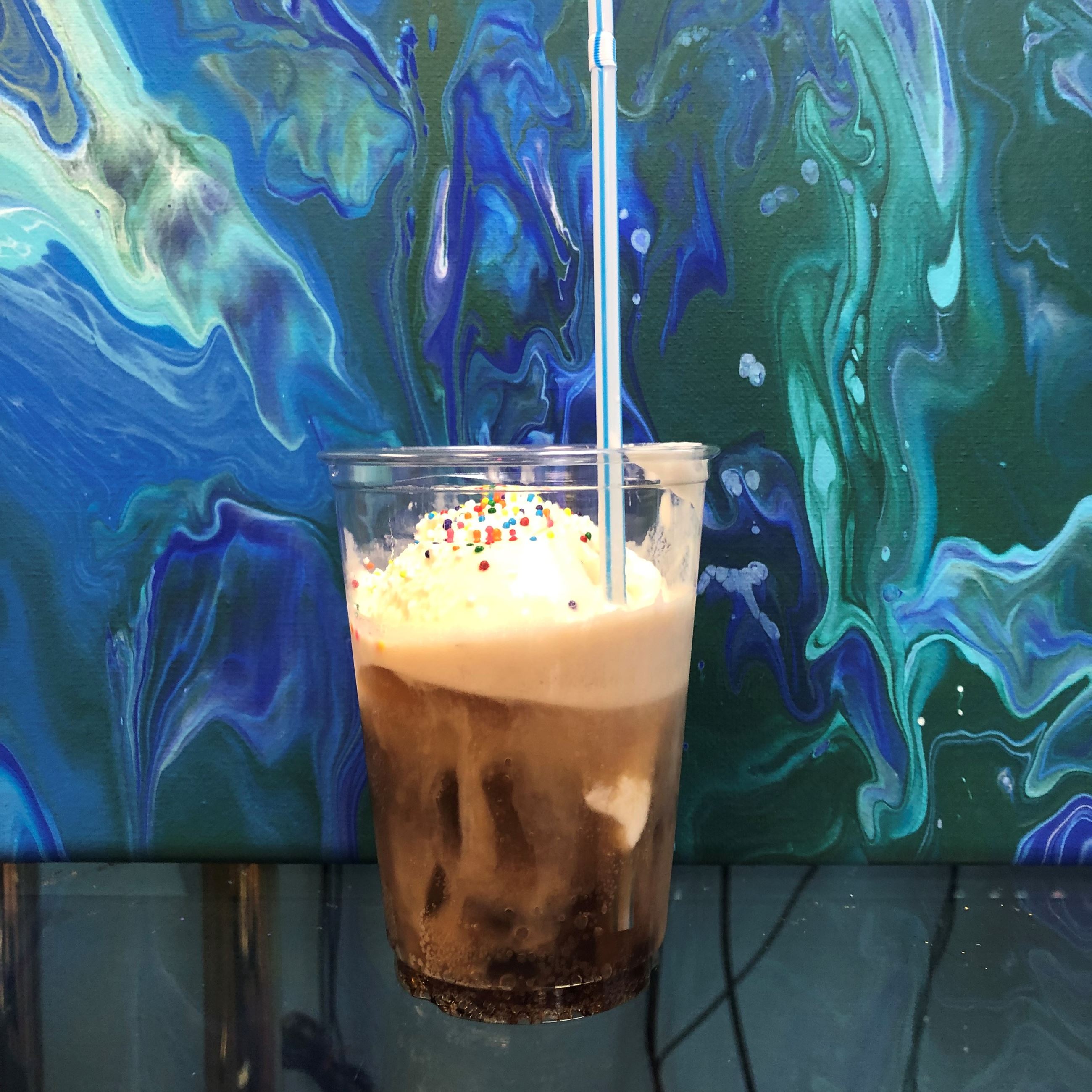 Clear cup filled with ice cream, sprinklers and soda